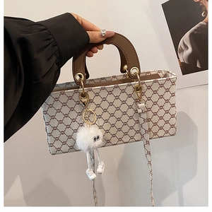Détail d'un sac à main rétro aux motifs de chaînes avec pompon en peluche et poignée ronde