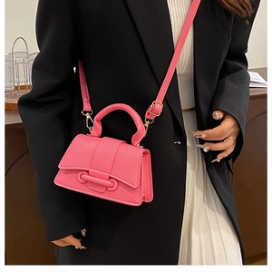 Detail of rose pink lychee leather mini crossbody bag with top handle and strap