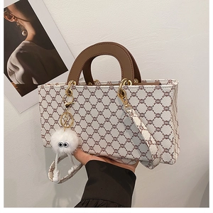Détail d'un cabas rétro à monogramme avec anses brunes et charm de sac en peluche