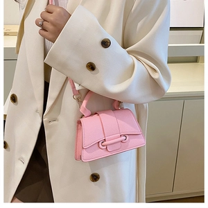 Close-up of pink mini crossbody bag with litchi texture on a white oversized blazer