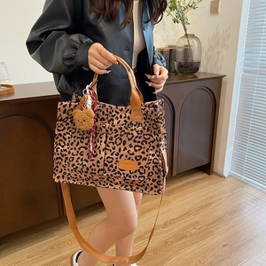 Leopard print canvas tote bag with brown handles and a plush bear charm for daily use