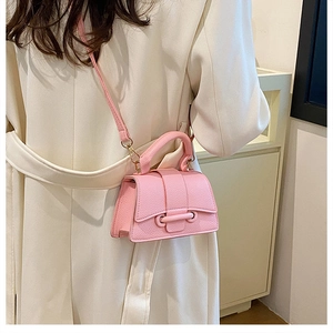 Detailed view of pink lychee leather mini handbag with top handle and crossbody strap