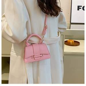 Pink lychee texture crossbody bag styled on white coat with adjustable strap detail