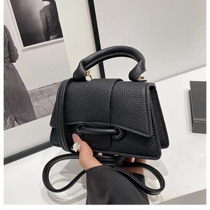 Detail of black lychee grain leather mini bag with gold hardware and top handle