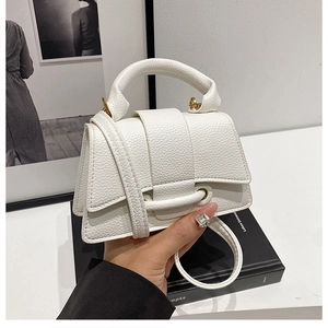 Detail of white mini crossbody bag featuring lychee texture and gold metal ring hardware