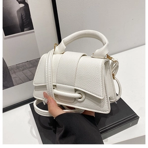 Detailed macro of white litchi pattern leather bag with gold hardware on black book