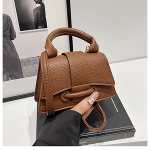 Detail of brown litchi pattern leather bag with top handle and crossbody strap