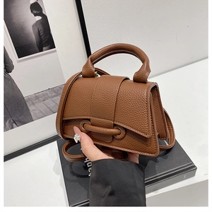 Detailed view of dark brown pebbled leather handbag with unique buckle strap detail