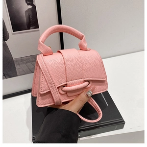 Detail of pink lychee grain leather handbag with stylish flap closure and thin shoulder strap