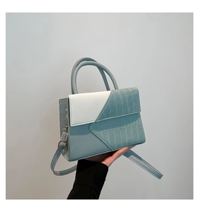 Détail du sac à main bicolore avec texture crocodile et finitions dorées