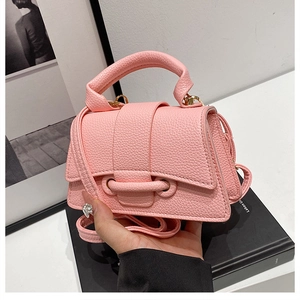 Close-up of pink lychee leather handbag featuring a bold belt buckle and gold-tone hardware