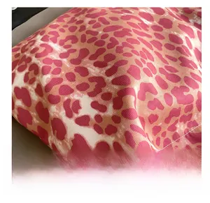 Close-up of leopard print fabric with orange and pink tones and white stitching