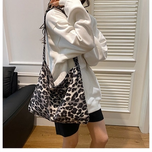 Large leopard print tote bag with wide strap worn by a model in a minimalist room
