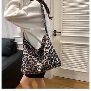 Detailed view of the leopard print tote bag being worn over the shoulder in a minimalist room