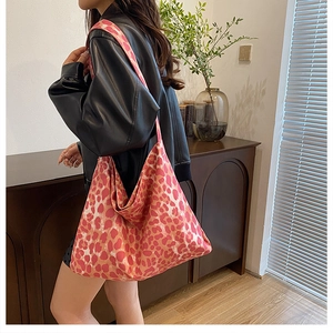 Detailed side view of large pink leopard print canvas tote bag shown with model