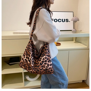 Side view of large leopard print tote bag with wide strap on model with grey hoodie
