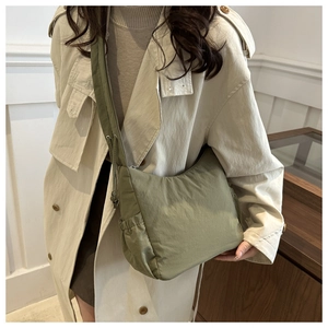Gros plan sur un sac bandoulière en nylon vert olive avec poche latérale à cordon coulissant