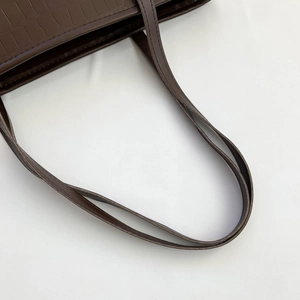 Detail of dark brown faux leather shoulder bag with embossed crocodile texture and stitching