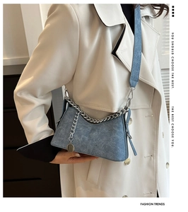 Detail of blue textured crescent bag with chunky silver chain and adjustable strap
