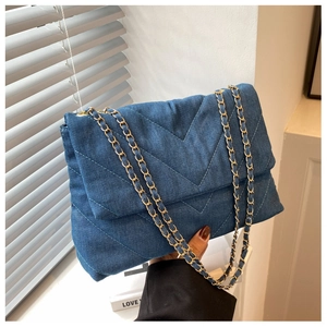 Détail du sac à bandoulière en denim bleu avec chaîne dorée et matelassage en V