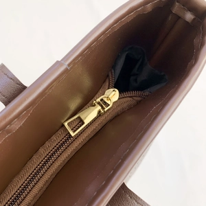 Detailed close-up of dark brown tote bag with premium golden zipper and black lining