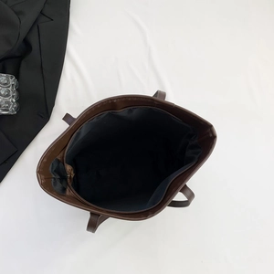 Detailed top view of the spacious inner compartment and zipper of the brown tote bag