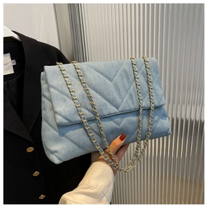 Détail du sac bandoulière bleu denim avec matelassage en V et chaîne en métal doré