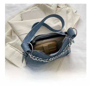 Interior view showing capacity of denim crescent bag with silver chain and metal corners