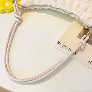 Detail of cream white bubble textured fabric bag with silver zipper and knot strap