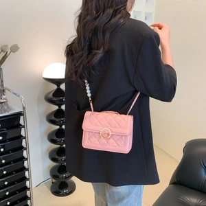 Sac bandoulière rose matelassé avec chaîne en perles et boucle dorée sur un modèle