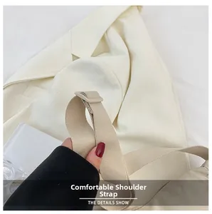 Detail of adjustable wide canvas shoulder strap on a beige nylon dumpling bag