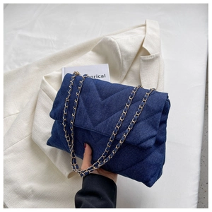 Détail du sac à bandoulière en denim bleu avec matelassage en V et chaîne dorée