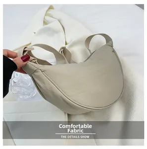 Close-up of the beige nylon dumpling bag showing soft fabric texture and minimal design