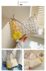 Detail of creamy white bubble textured shoulder bag with a yellow sunflower charm