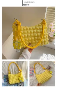 Detail view of yellow puffy shoulder bag with bubble texture and knotted strap