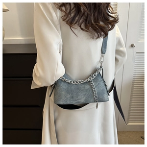Close-up of denim textured crescent bag with silver chain detail on trench coat