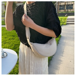 Detail of beige nylon half-moon crossbody bag with adjustable wide strap on outdoor model