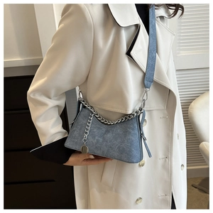 Detailed view of blue denim texture crossbody bag with silver chain on model