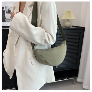 Detailed view of olive green nylon crescent bag with wide shoulder strap on model