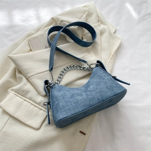 Close-up of denim crescent bag featuring vintage silver chain and textured fabric detail