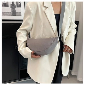 Detailed view of gray nylon crescent bag styled with a white oversized blazer