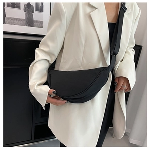 Detailed view of a black nylon crescent crossbody bag worn with a white blazer