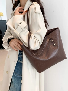Deep brown crocodile embossed tote bag with gold rivets for daily office commute
