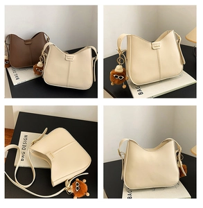 Close-up of minimalist crossbody bag with FASHION gold label and plush bear charm