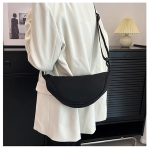 Minimalist black nylon half-moon shoulder bag displayed in a stylish modern interior