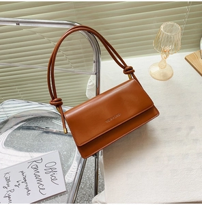 Detail of caramel leather baguette bag with knotted shoulder strap and gold hardware