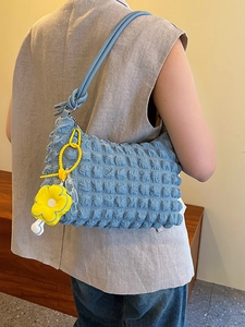 Minimalist light blue bubble textured shoulder bag with a yellow flower charm on model