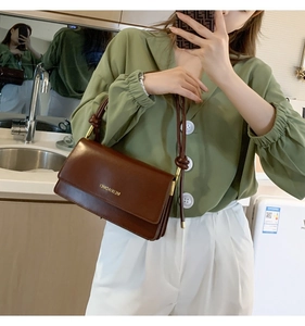 Detailed close-up of brown vintage matte leather bag with unique knotted strap design