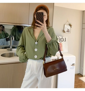 Detailed side view of a brown faux leather baguette bag with a gold metal chain strap