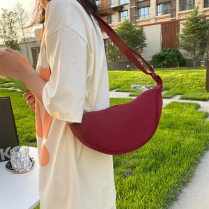 Minimalist burgundy nylon crescent shoulder bag with adjustable strap worn by model